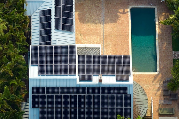 Casa residencial americana costosa con azotea cubierta con paneles solares fotovoltaicos para producir energía eléctrica ecológica limpia en el área rural suburbana Concepto de hogar autónomo