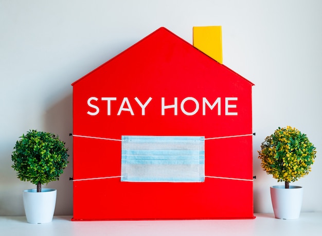 Foto casa roja con un mensaje y una máscara médica. concepto de distancia social, educación a distancia, educación en el hogar, coronavirus, cuarentena.