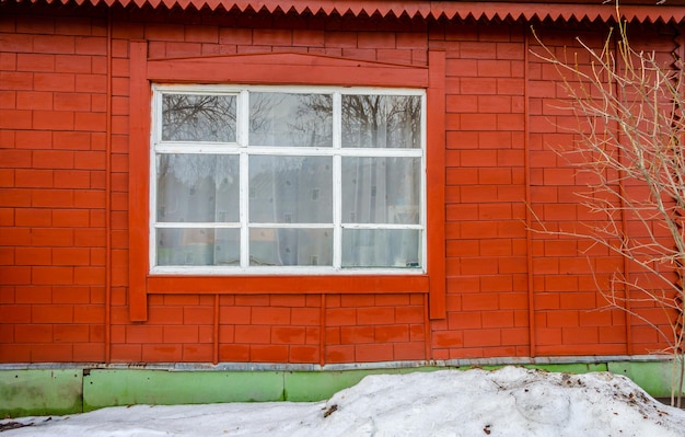 Una casa roja con una ventana blanca y una pared verde.