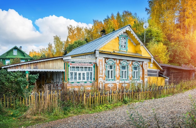 Casa rusa de madera con ventanas de encaje en otoño Plyos