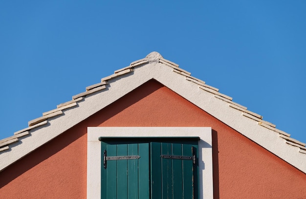 La casa sobre el fondo del cielo azul Techo y ventana con persianas Composición arquitectónica Diseño e ideas