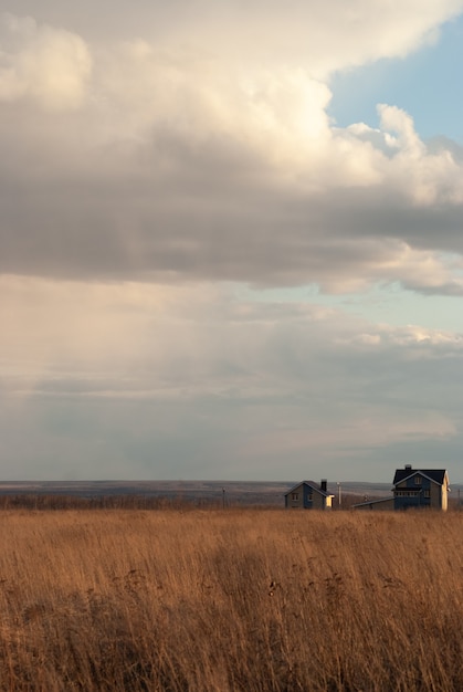 Casa solitária em um campo verde florido durante o pôr do sol quente de verão