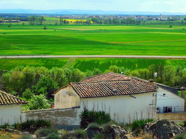 Una casa con techo rojo y un campo verde al fondo.