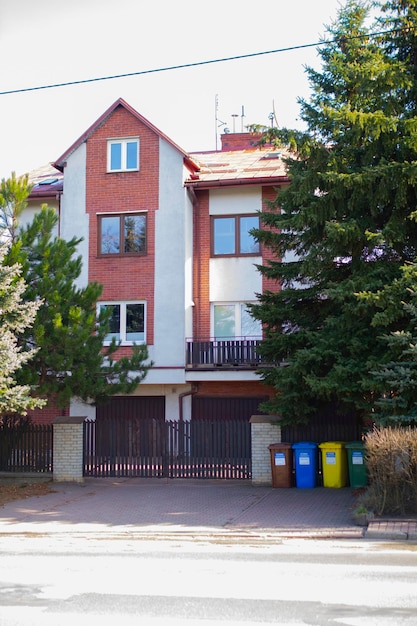 Una casa con techo rojo y ventanas y árboles verdes cerca