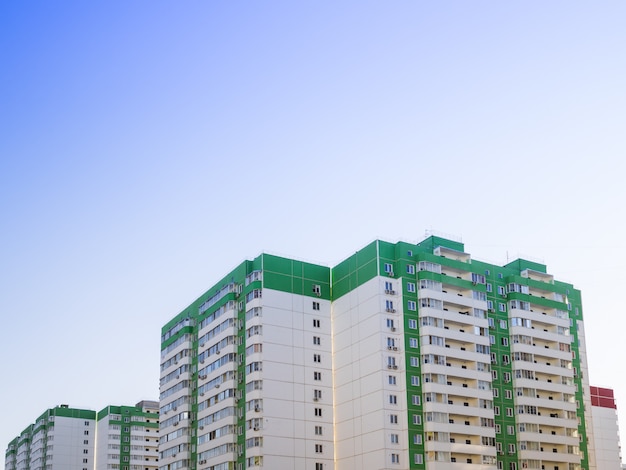 La casa de varios pisos es verde contra un cielo azul claro.