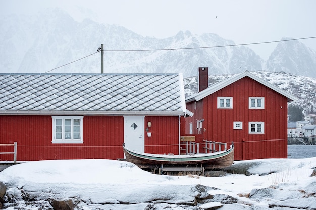 Casa vermelha de madeira da aldeia piscatória em neve coberta no inverno nas ilhas Lofoten Noruega