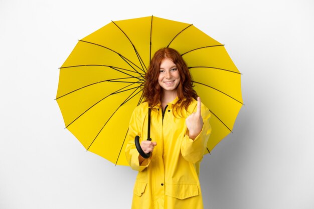 Casaco à prova de chuva e guarda-chuva da menina ruiva adolescente isolado no fundo branco fazendo gesto de aproximação