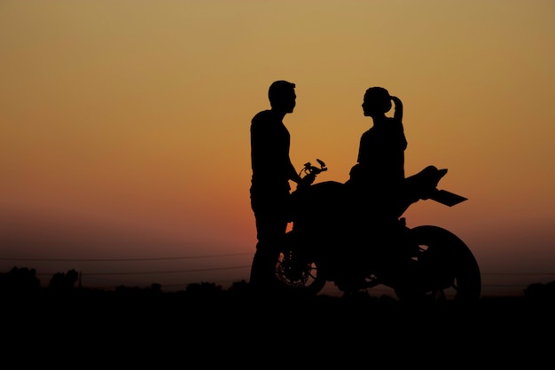 Casais com uma motocicleta ao pôr do sol