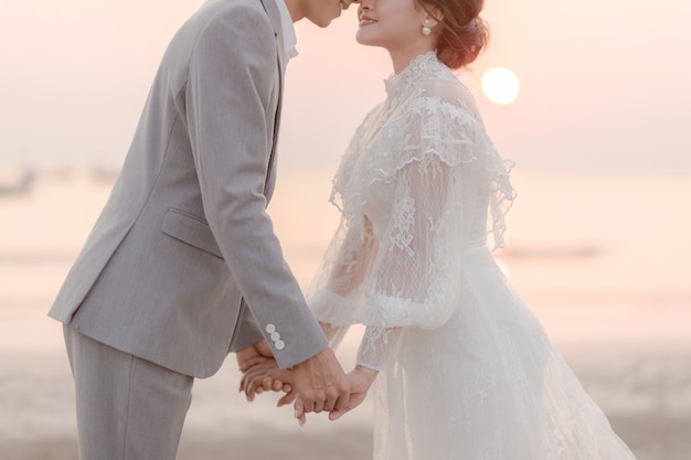 Casais de mãos dadas e beijando na praia à beira-mar. conceito de amor