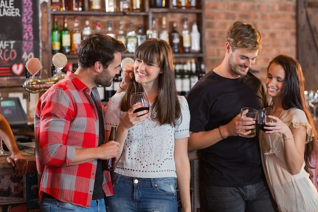 Casais jovens segurando bebidas em bar