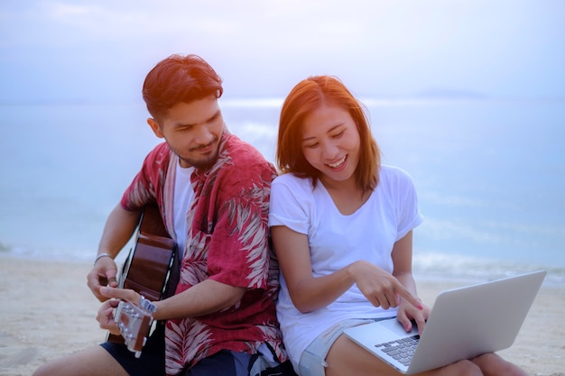 Casais jovens tocando música e cantando juntos na praia