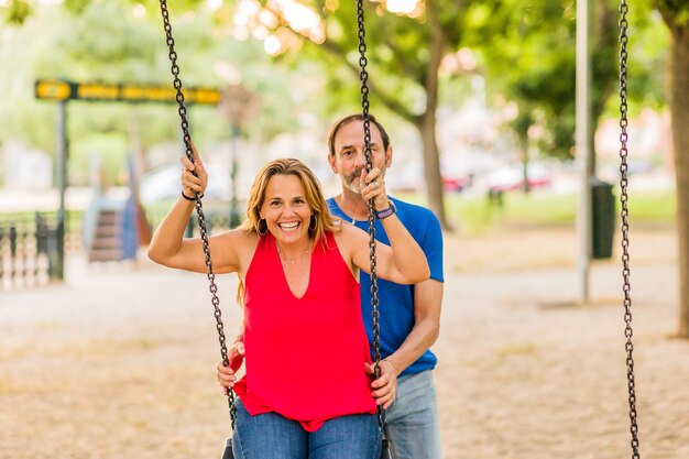 Casais maduros casados desfrutam felizes no balanço do parquinho, idosos, liberdade, amor e felicidade