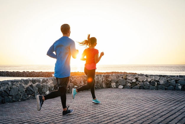 Casal a correr no calçadão contra o céu claro durante o pôr-do-sol