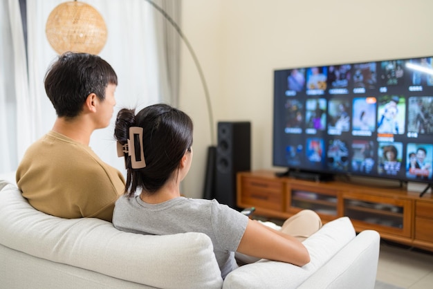 Foto casal a ver televisão em casa.