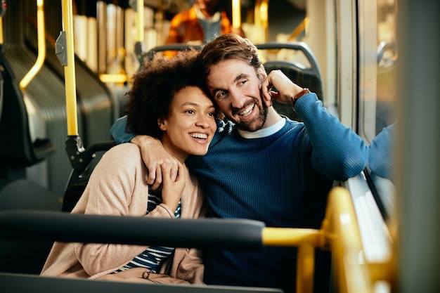 Casal abraçado olhando pela janela enquanto viaja de ônibus