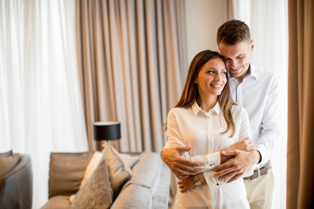 Casal abraçando em pé na sala de um apartamento contemporâneo