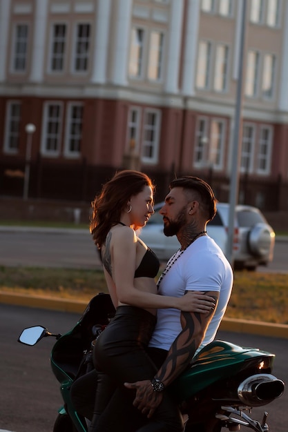 Casal abraçando perto de moto ao pôr do sol