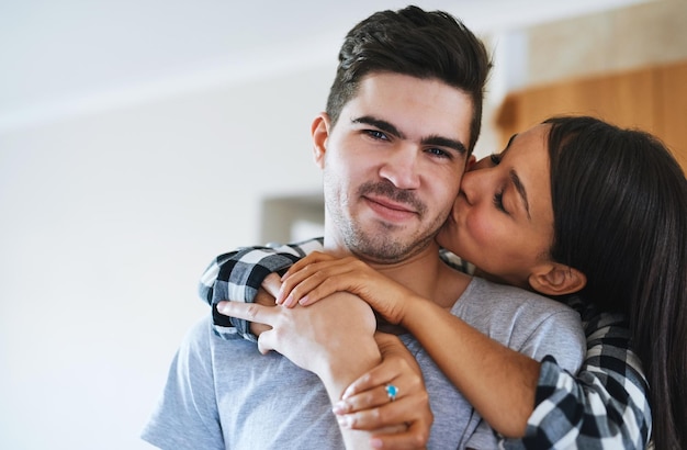 Casal abraçar e beijar na bochecha em casa para relacionamento romance ou ligação juntos no fim de semana Amor homem feliz e mulher com afeição para abraçar apoio ou vida conjugal com cuidado no apartamento