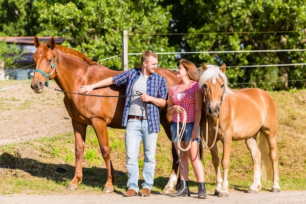 Casal acariciando cavalo no estábulo de pônei