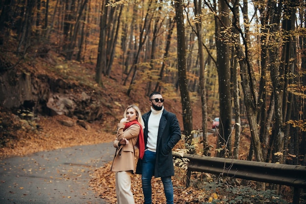 Casal adorável da moda caminhando pelo parque durante o outono