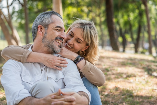 Casal adorável e feliz, abraçando juntos, sentado no parque