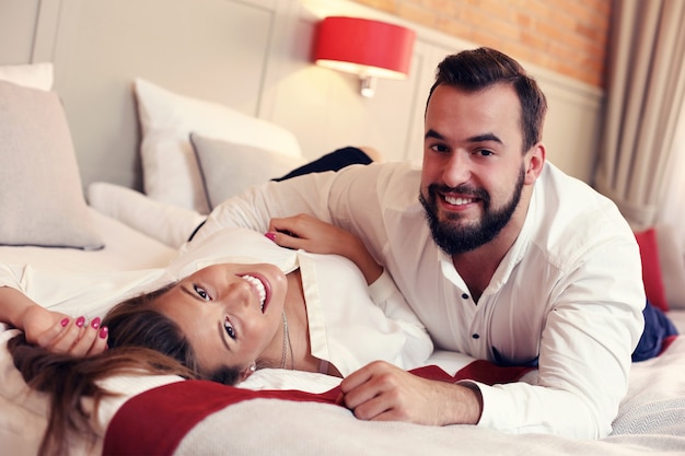 Foto casal adulto em traje de negócios deitado na cama do hotel