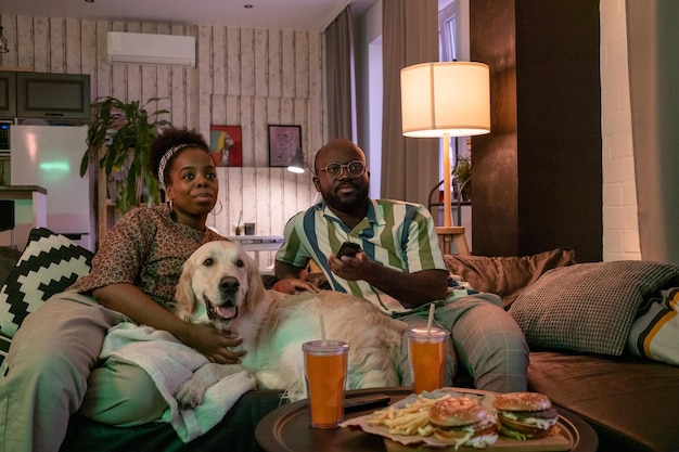 Casal africano sentado em casa com cachorro