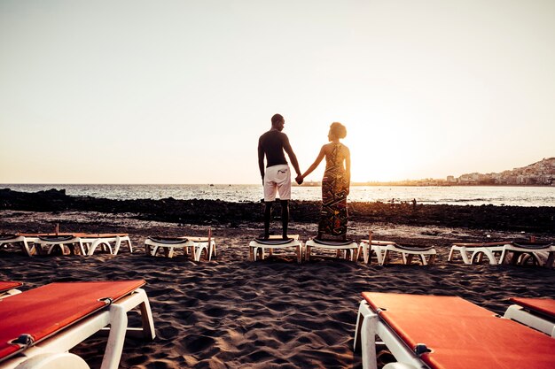 Casal afro-americano de raça negra se divertindo e brincando juntos na caminhada perto da praia. conceito de felicidade de férias para dois lindos rapazes e moças