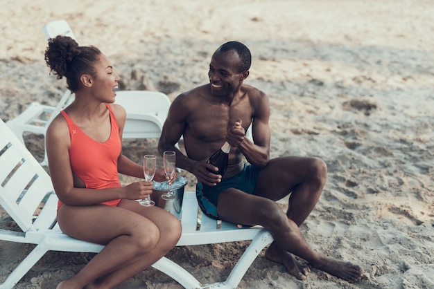 Casal afro-americano está descansando na praia do rio