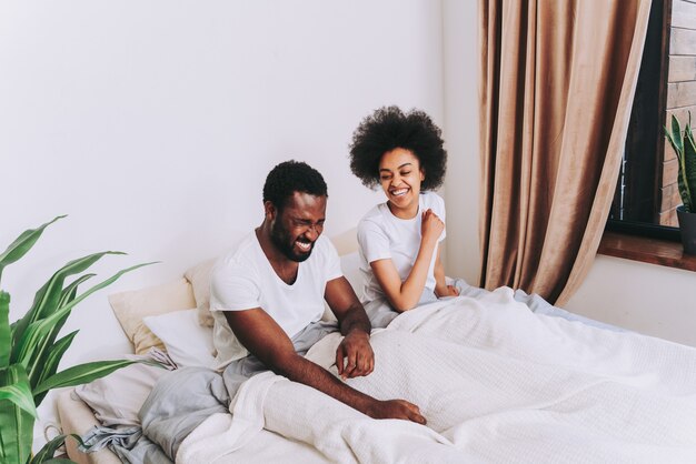 Casal afro-americano na cama - casal de namorados lindos e alegres em casa