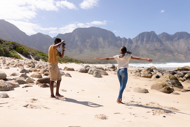 Casal afro-americano tirando fotos em uma praia à beira-mar. estilo de vida saudável, lazer na natureza.