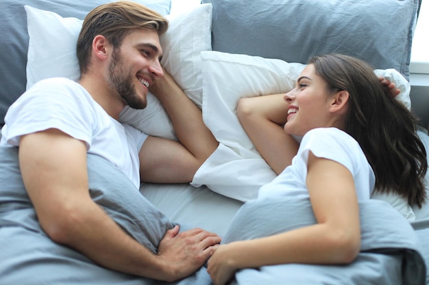 Casal alegre acordando e olhando um para o outro na cama.