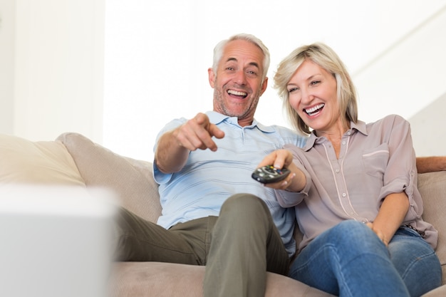 Casal alegre assistindo TV em casa