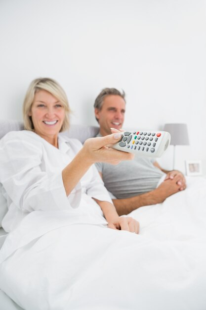 Casal alegre assistindo tv na cama