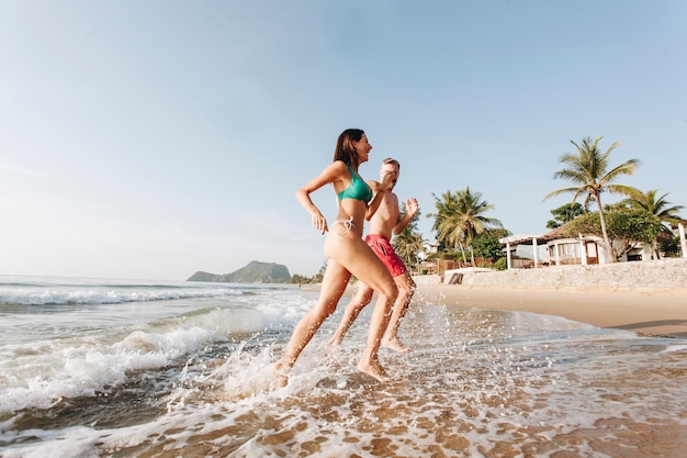 Casal alegre correndo na praia