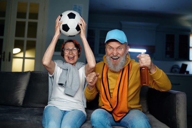 Foto casal alegre da família sênior assistindo jogo de futebol na tv em casa