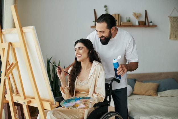 Casal alegre de homem barbudo e mulher deficiente pintando em cavaleiro juntos em casa