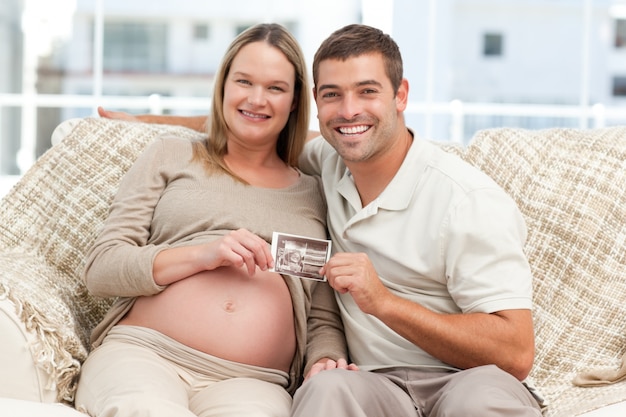 Casal alegre dos futuros pais segurando uma ecografia