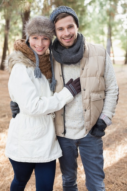 Casal alegre em roupas de inverno na floresta