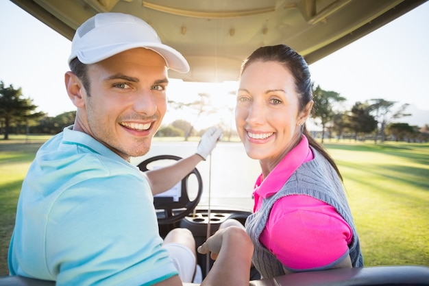 Casal alegre golfista sentado no carrinho de golfe