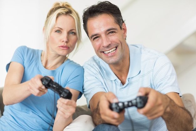 Casal alegre jogando videogames na sala de estar