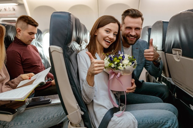 Casal alegre mostrando gesto de aprovação no avião