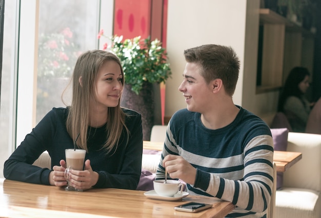 Casal alegre namorando em um café. eles estão se divertindo e sorrindo. eles estão olhando um para o outro.