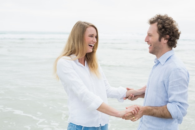 Casal alegre olhando um para o outro na praia