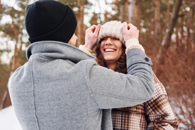 Casal alegre passear na floresta de inverno durante o dia