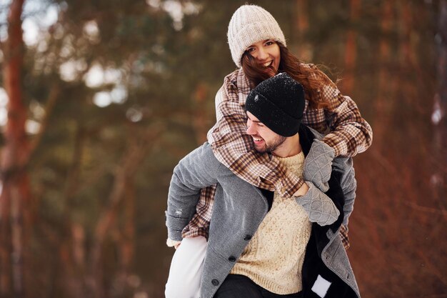 Casal alegre passear na floresta de inverno durante o dia