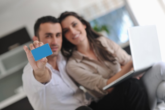 Foto casal alegre relaxa e trabalha no computador portátil na sala de estar moderna em casa