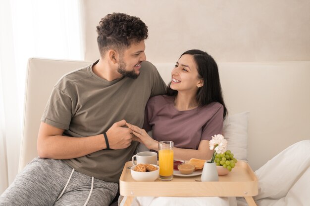 Casal alegre tomando café da manhã e lua de mel no quarto do hotel