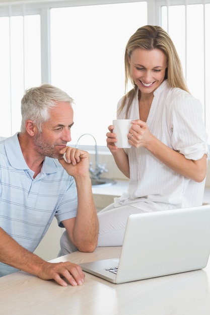 Casal alegre usando o laptop juntos no balcão