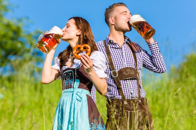 Casal alemão em Tracht com cerveja e pretzel